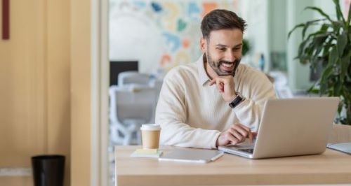 Happy man enjoying remote work on laptop in office